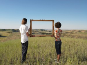 A man and woman hold up a frame together in a field