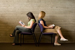 Two women read books, facing away from each other.