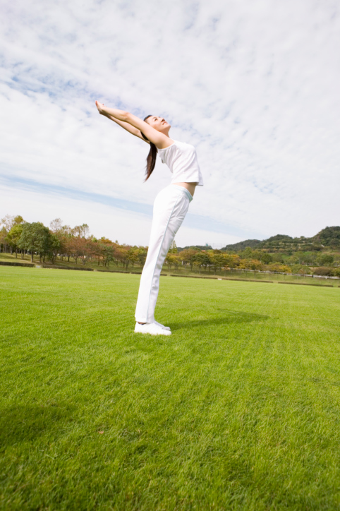 A woman does yoga stretches in a field