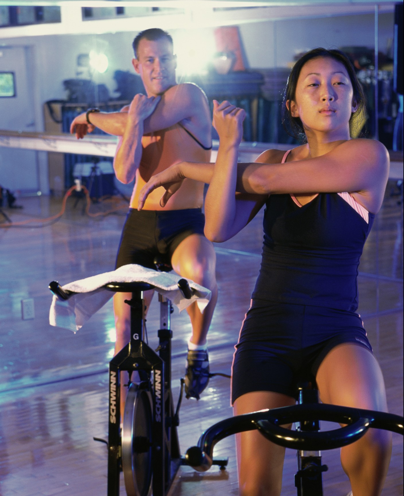 Two people stretching on stationary bikes