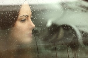 Woman looks sadly through car window
