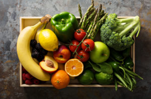 Overhead view of fresh and colorful vegetables and fruits in a wooden crate