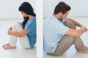 Couple sitting on opposite sides of a wall