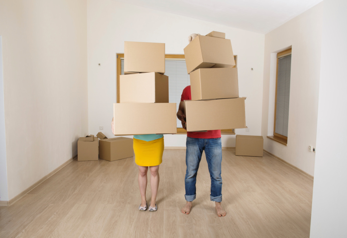 Moving couple holds stacks of boxes
