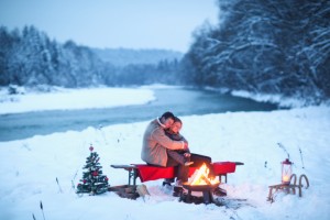 Couple sitting bycampfire in snow