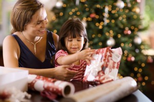 Mother and daughter opening presents by tree