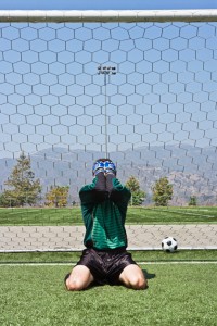 Goalie mourns scored goal, covering face with hands