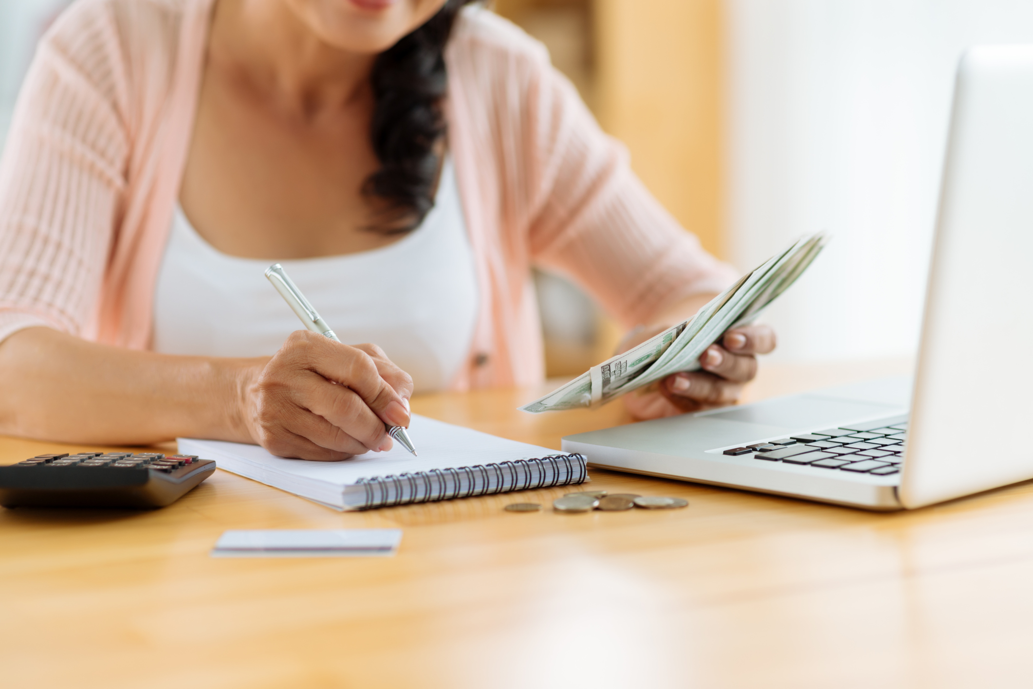 Woman holding money and writing down budget