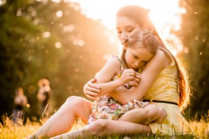 Mother and worried daughter sit on grass