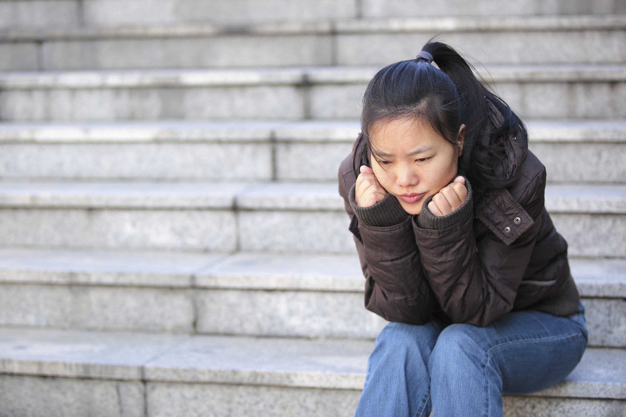 A woman sitting alone on outside stairs