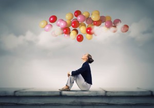 Woman on roof looks up at bright balloons