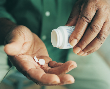 Close-up of hands shaking pills out of a bottle