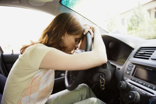 Stressed woman leaning head on car steering wheel