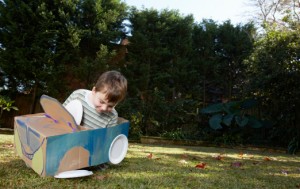 Boy plays in car made from box and paper plates