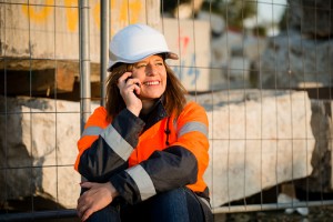 Smiling construction worker using phone on break