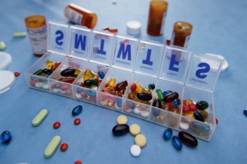 Assortment of pills in pill box and scattered on table
