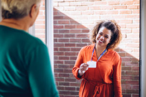 Social worker shows name tag at door of client