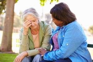 Woman comforts sad friend on bench