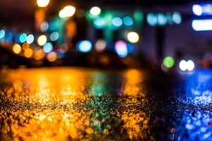 Rain-soaked street with blurred lights in the background