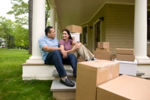 Happy couple with boxes, talking on porch