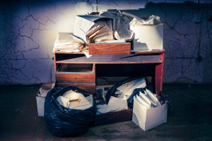 Desk stacked with bags and boxes of papers