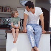 Father and son sitting on kitchen counter