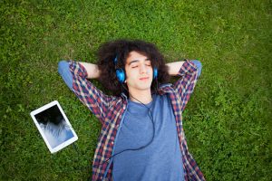 Teen listening to music lying on grass