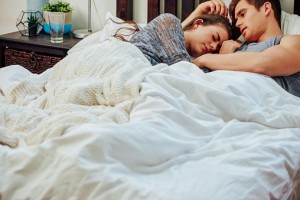 Sad woman being comforted by partner in bed