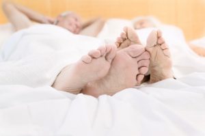 closeup on feet of couple lying in bed