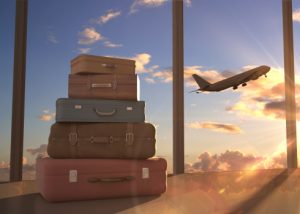 Suitcases stacked by window showing airplane in sky