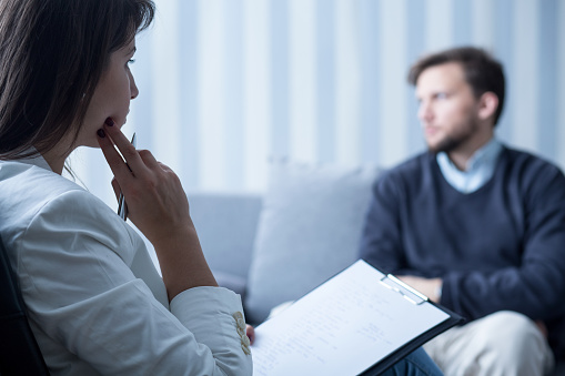 Therapist looks at person in treatment thoughtfully