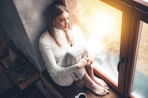 Serious woman sits in window looking out