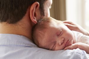 Father with newborn infant sleeping