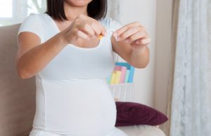 Pregnant woman breaking a cigarette