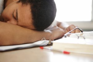 Student sleeping on textbooks