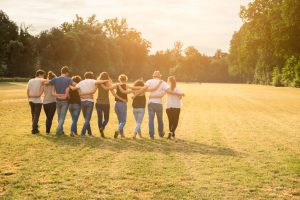 Rear view of ten people in a field with linked hands