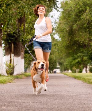 Action shot of young woman happily jogging with dog