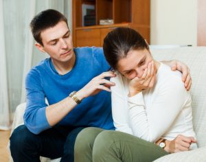 Man consoling sad woman on sofa