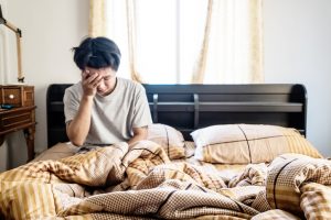 Young man wakes up in bed with head pain