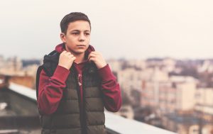 Serious teenage boy stands alone on roof