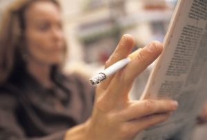 Close-up of cigarette while reading the newspaper