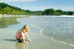 A small child crouches in waves at the seashore