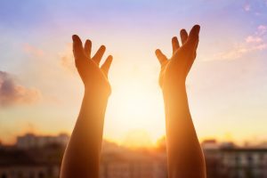 City background at sunset with hands raised in foreground