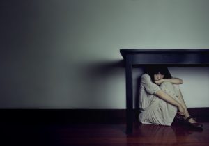 Frightened person hides under table