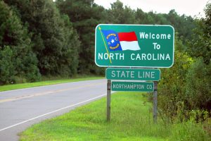 An empty road with a 'Welcome to North Carolina' sign