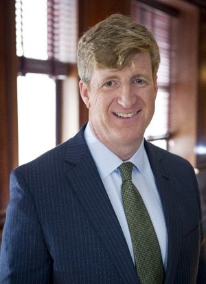 Patrick Kennedy standing in front of a window wearing a suit