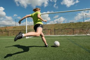 Woman about to kick soccer ball into net