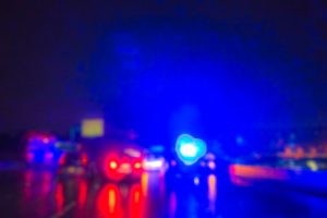 Blurred image of police cars with lights on rainy night