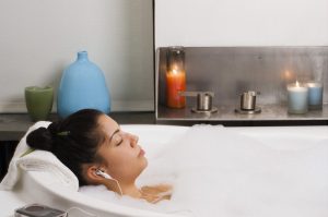 Person listens to music in bubble bath with eyes closed