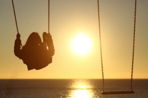 Rear view of a person on swing over the ocean